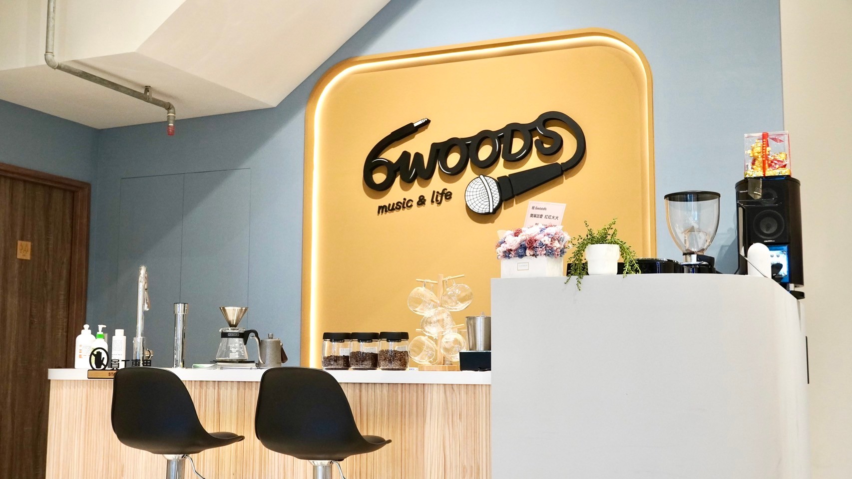 6WOODS 音樂教室溫馨休息交流區,木質吧檯搭配品牌牆,營造放鬆自在的氛圍
